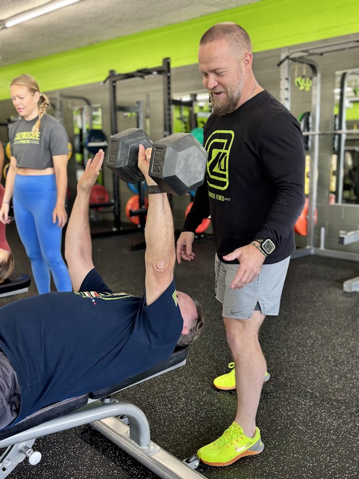 Coach Matthew Cather spotting a member during dumbbell bench press